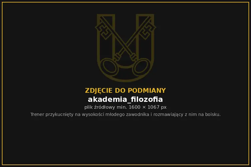 Trener Akademii rozmawia z młodym zawodnikiem na boisku